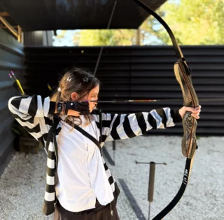Young girl aiming a bow during archery session
